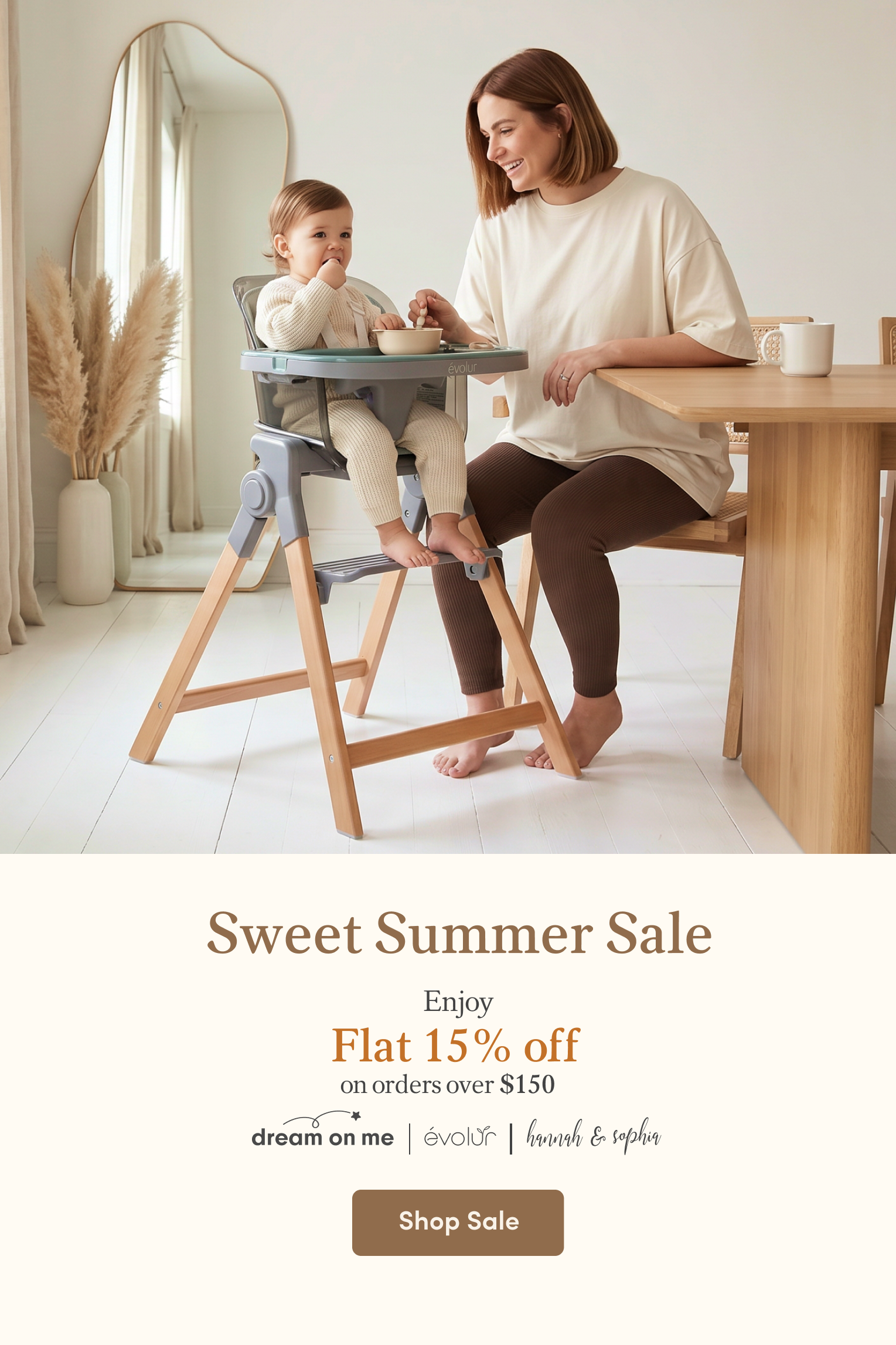 A smiling woman feeds a baby sitting in a gray and wood high chair.