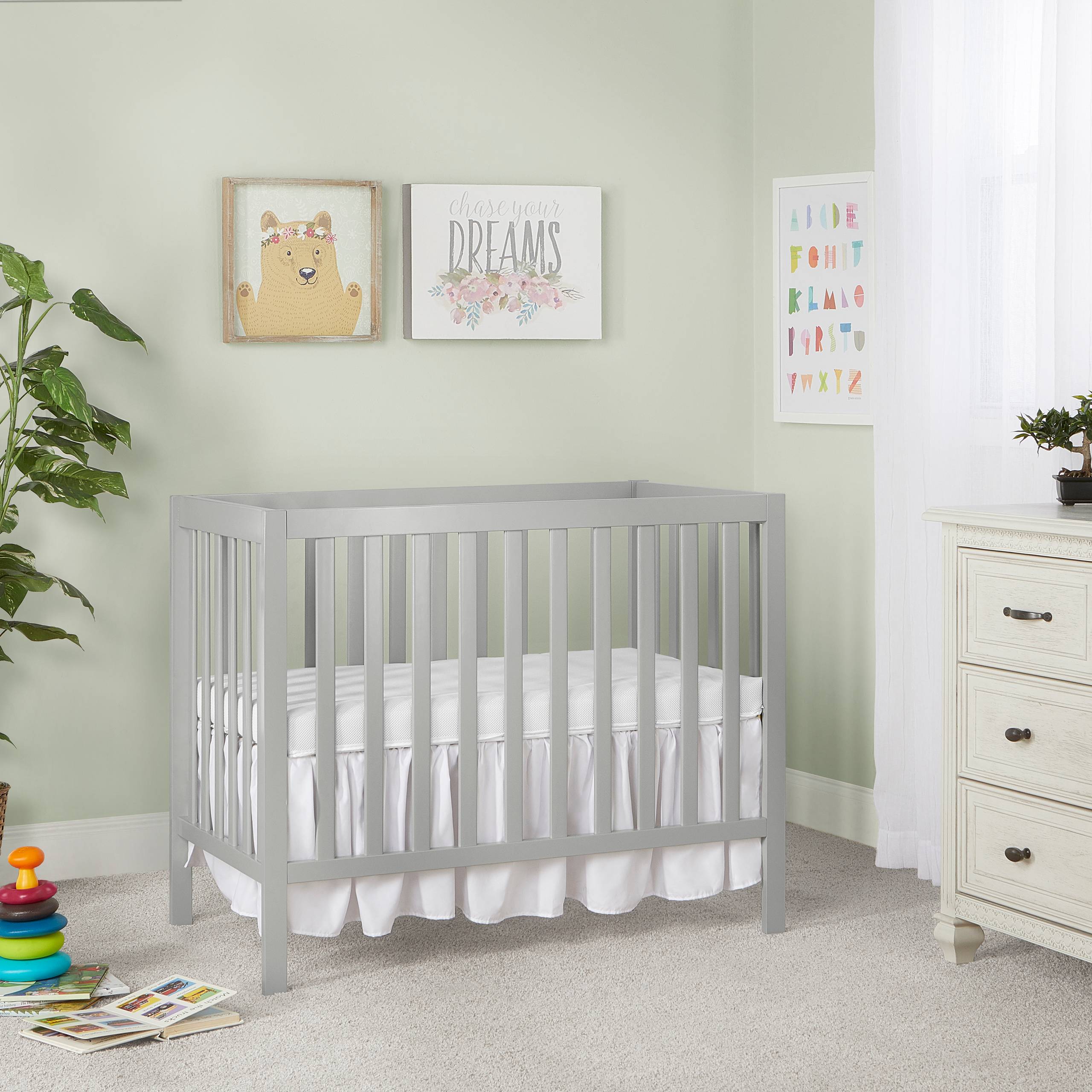 Dream On Me Edgewood 4-in-1cool gray baby crib with slatted design and white bedding, modern nursery furniture placed against a pastel green wall