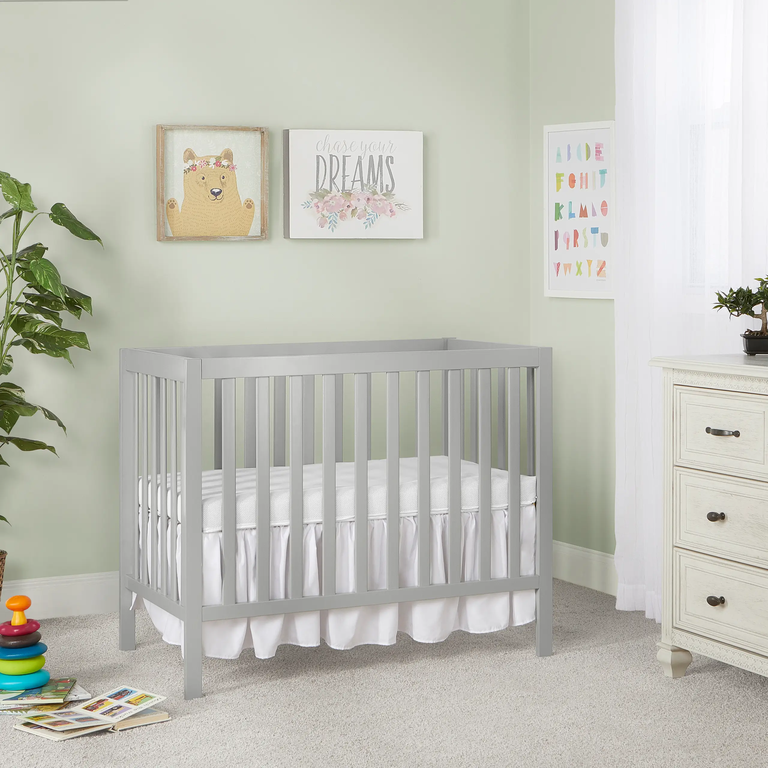 Dream On Me Edgewood 4-in-1cool gray baby crib with slatted design and white bedding, modern nursery furniture placed against a pastel green wall