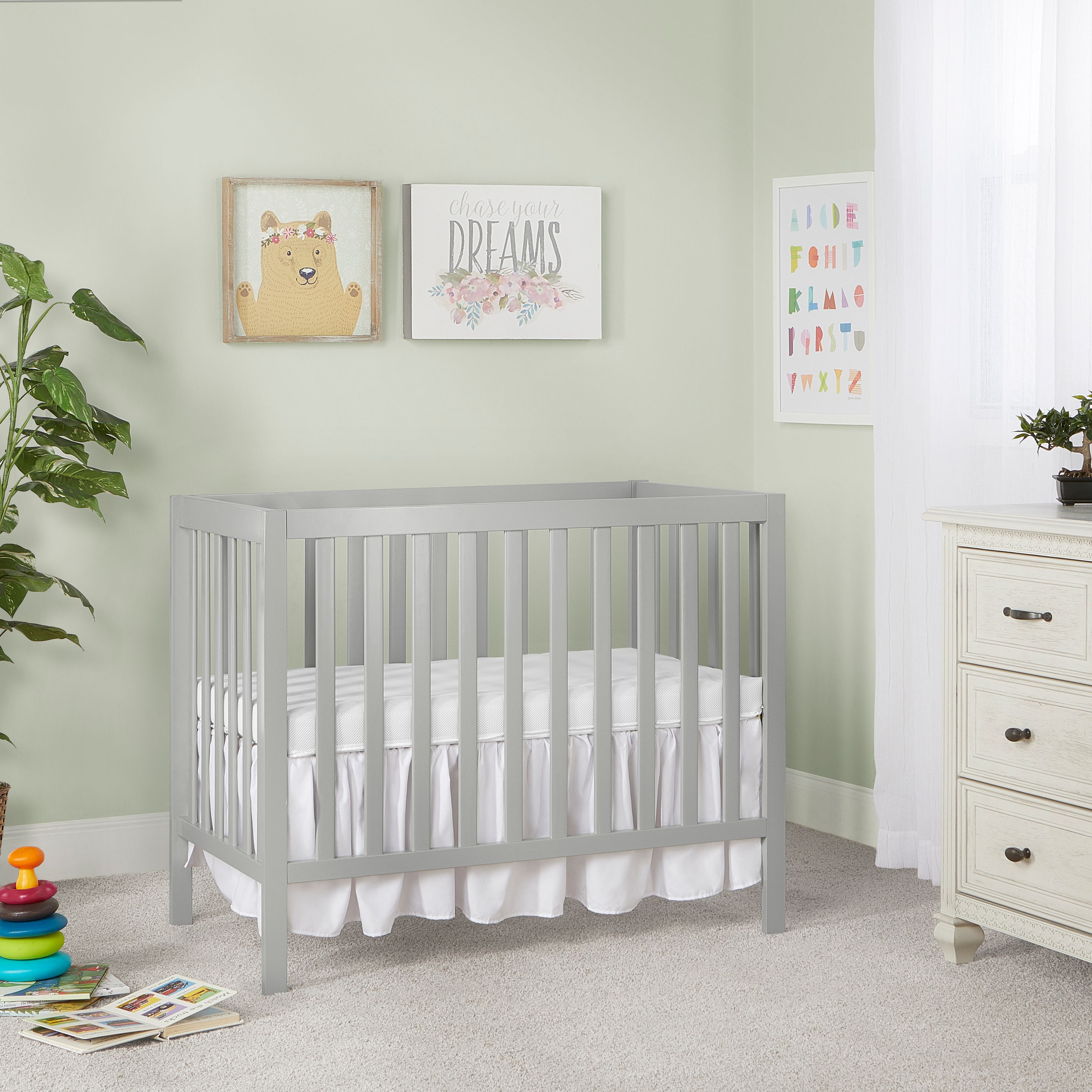 Dream On Me Edgewood 4-in-1cool gray baby crib with slatted design and white bedding, modern nursery furniture placed against a pastel green wall