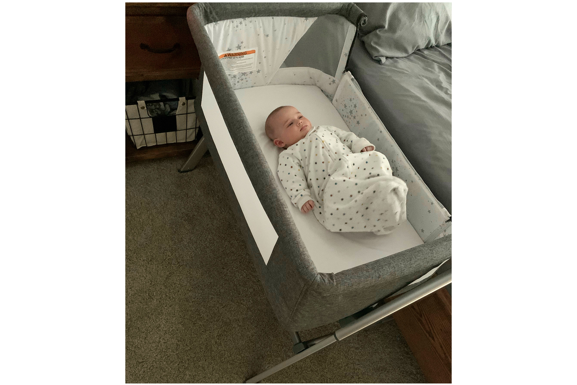 Newborn lying safely in Dream On Mr Skylar bedside bassinet in modern bedroom