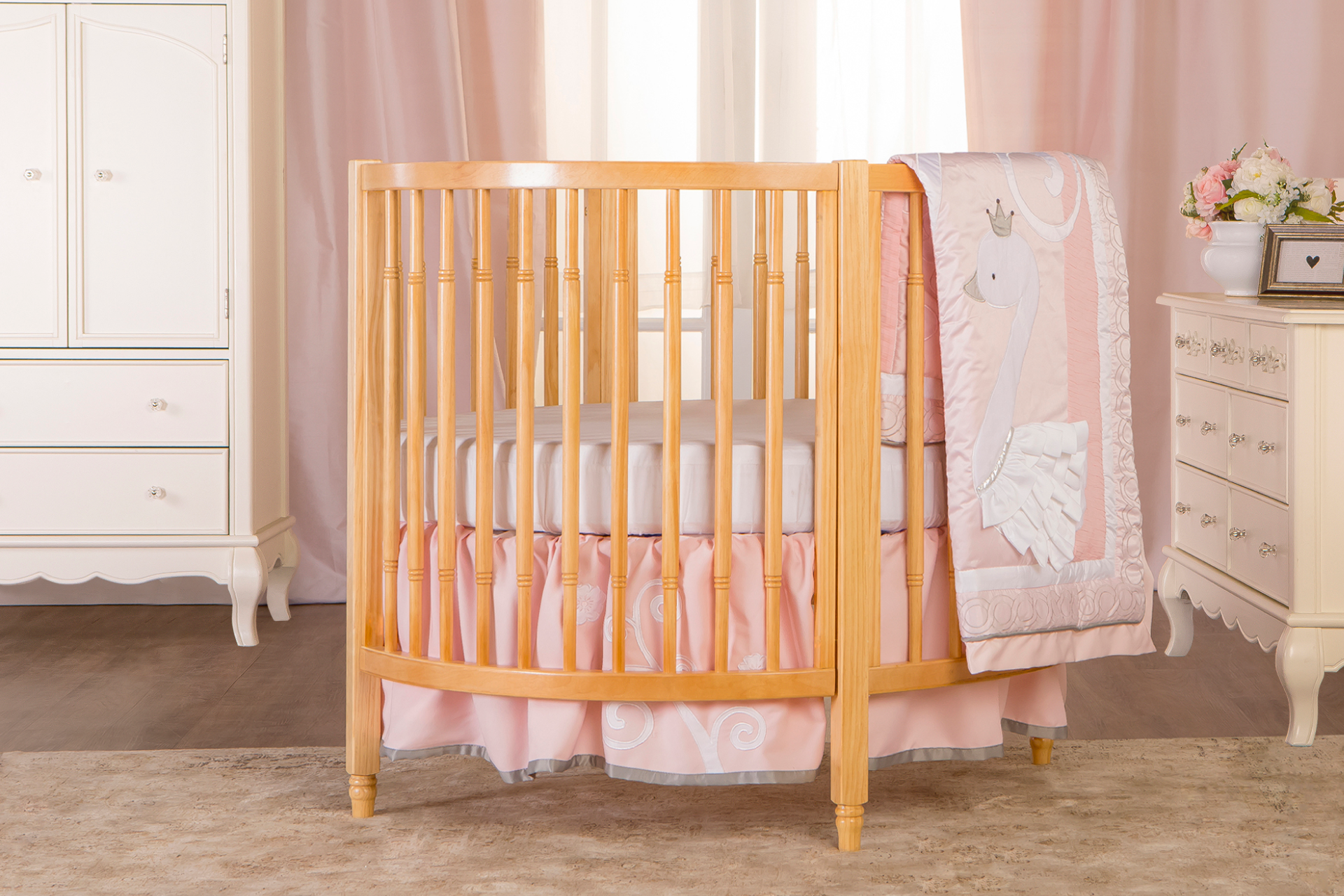 Dream On Me Sophia Posh Circular Crib with vertical slats and pink bed skirt featuring white embroidered swirls
