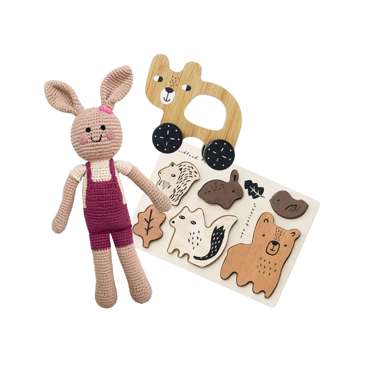 A crocheted bunny doll, a wooden bear-shaped car toy, and a wooden woodland animal puzzle.