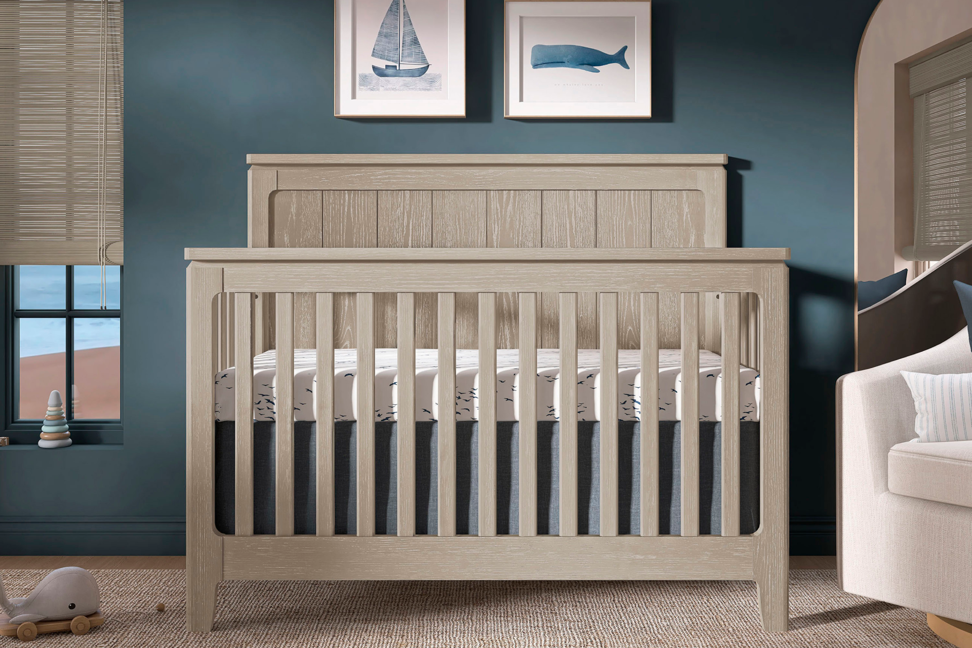 Evolur Oakley crib in a nautical-themed nursery with ocean artwork, deep blue walls, and coastal-inspired decor