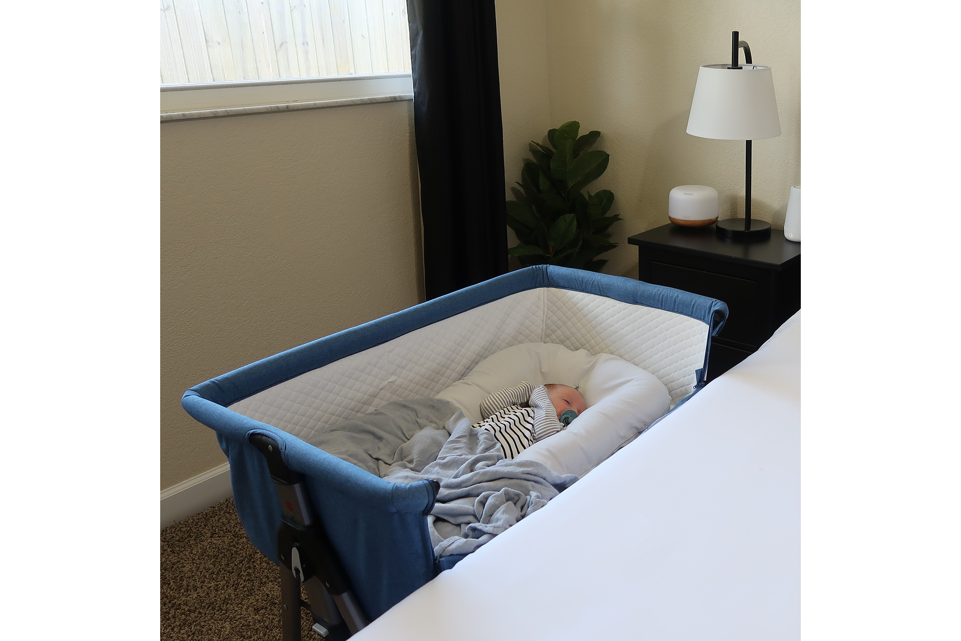 Peaceful baby sleeping in Dream On Me Lotus bedside bassinet in cozy bedroom with soft lighting and natural décor