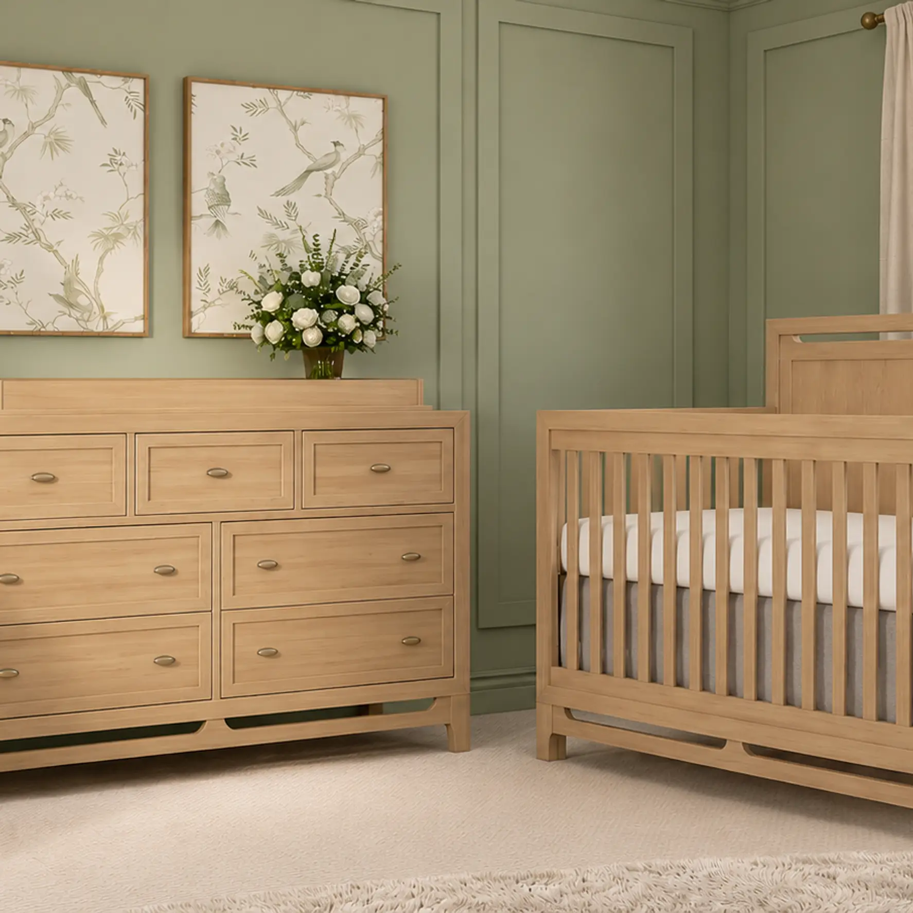 A serene sage green nursery with a natural wood crib, matching dresser with a changing top, and a cream glider.