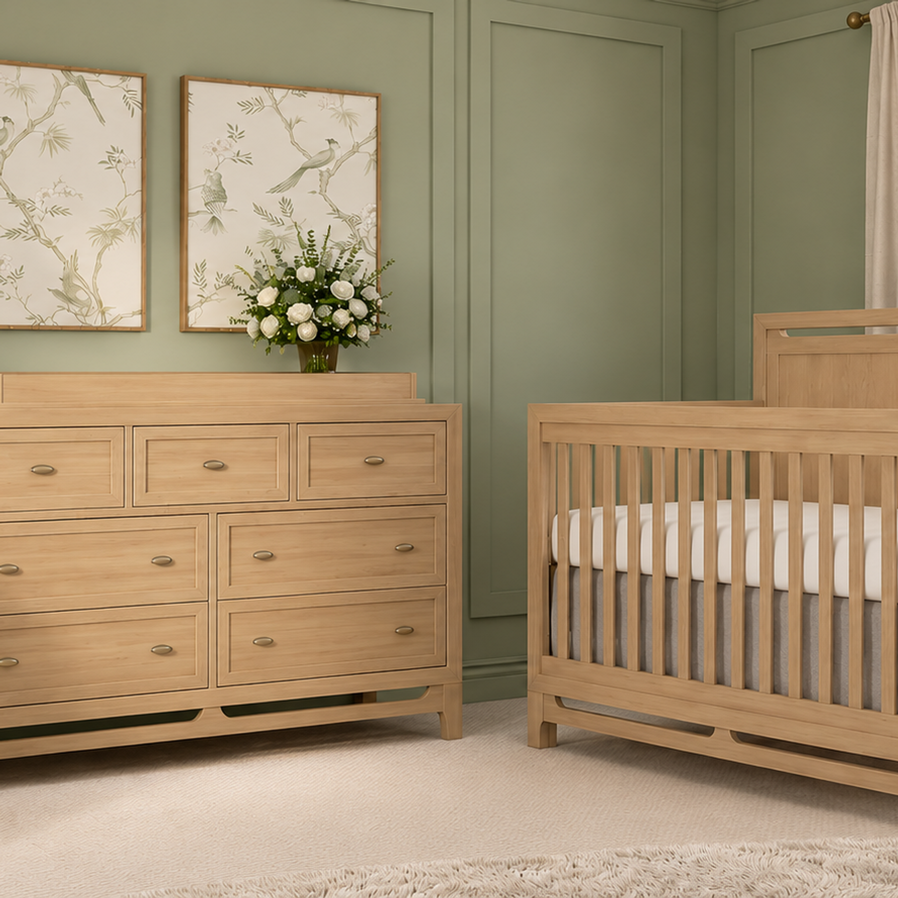 A serene sage green nursery with a natural wood crib, matching dresser with a changing top, and a cream glider.