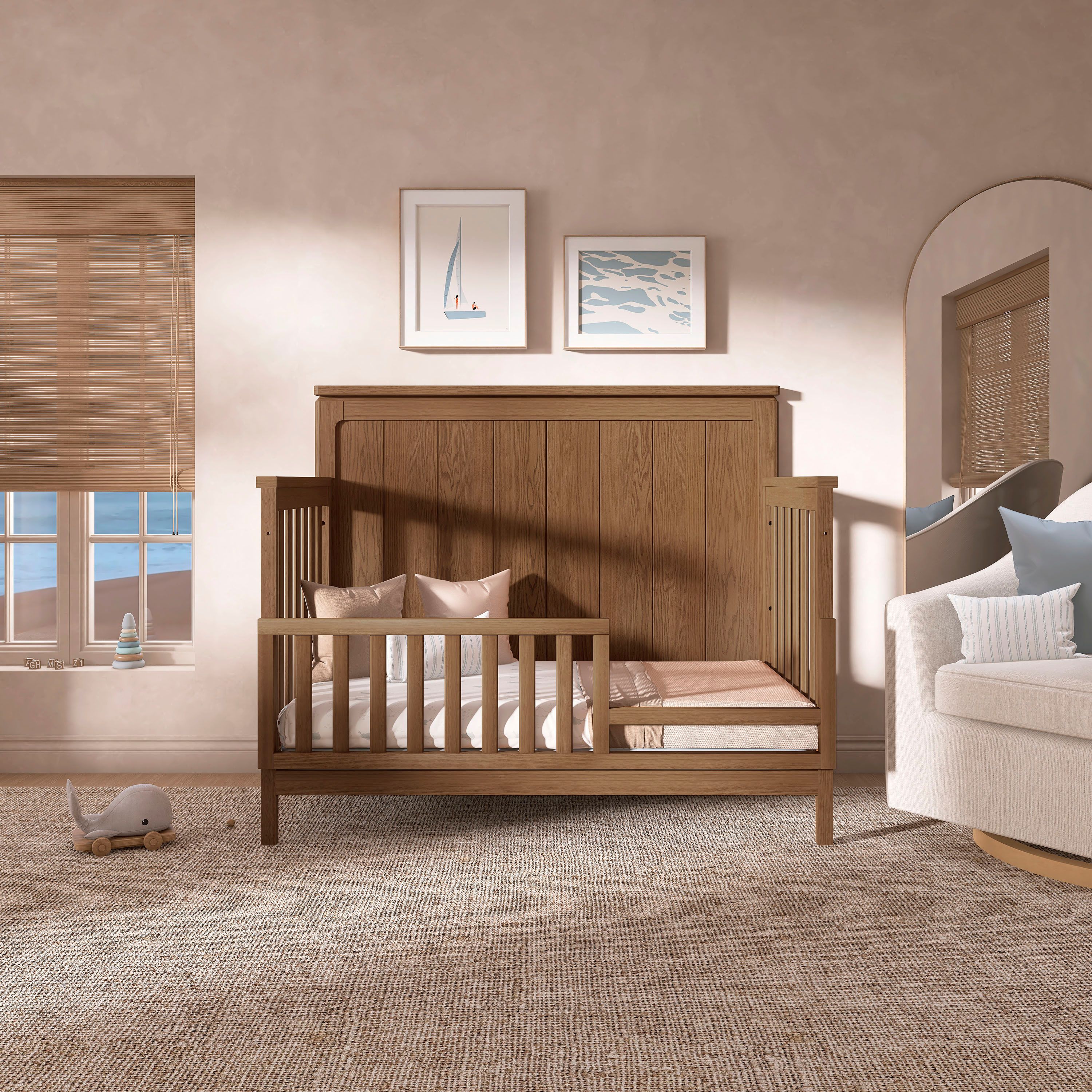Evolur Oakley 5-in-1 Convertible Crib in a cozy, minimalist nursery with neutral tones and coastal wall art showcasing the crib convertibility to toddler bed