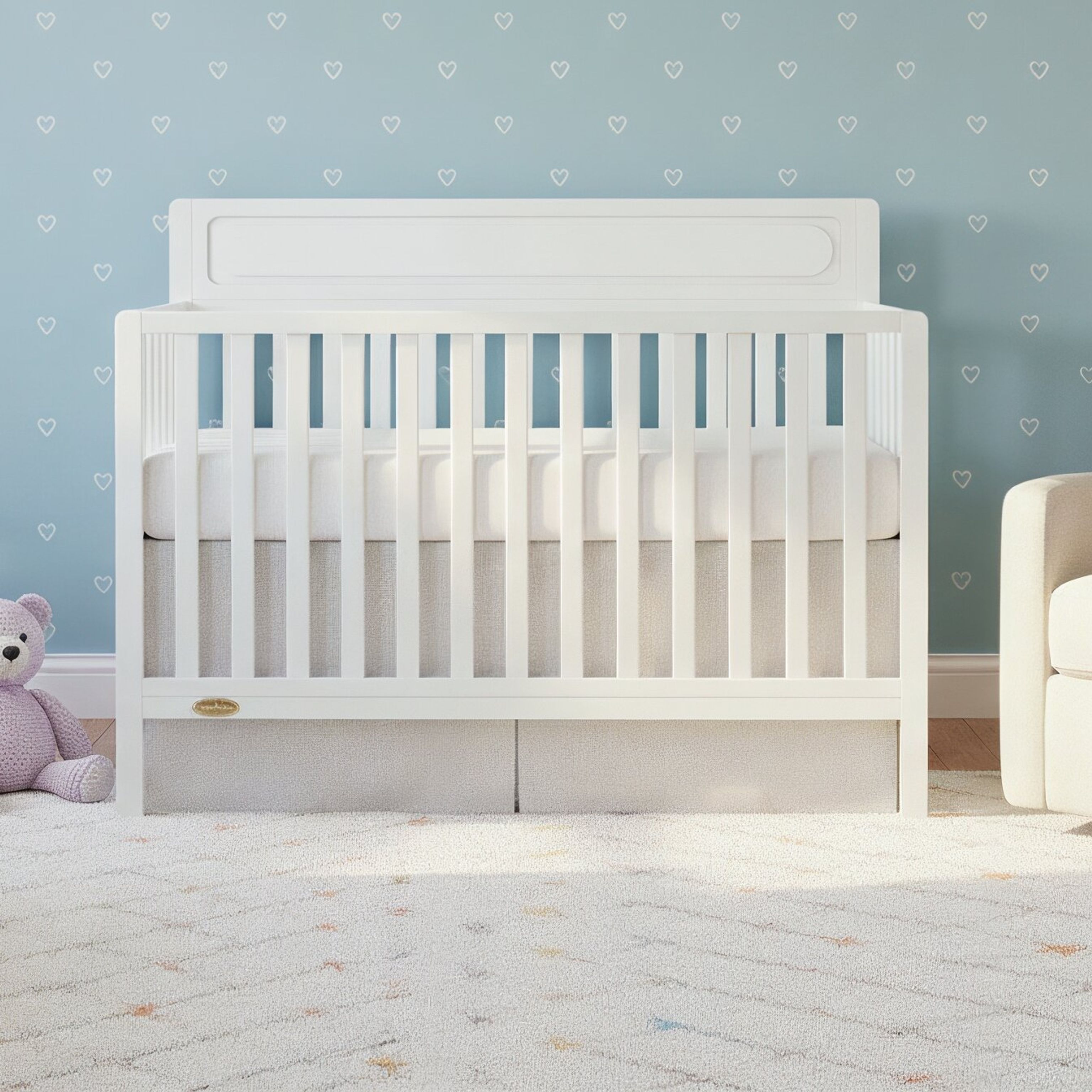 Modern baby nursery with a white crib, pastel blue wall with heart prints, soft rug, and armchair