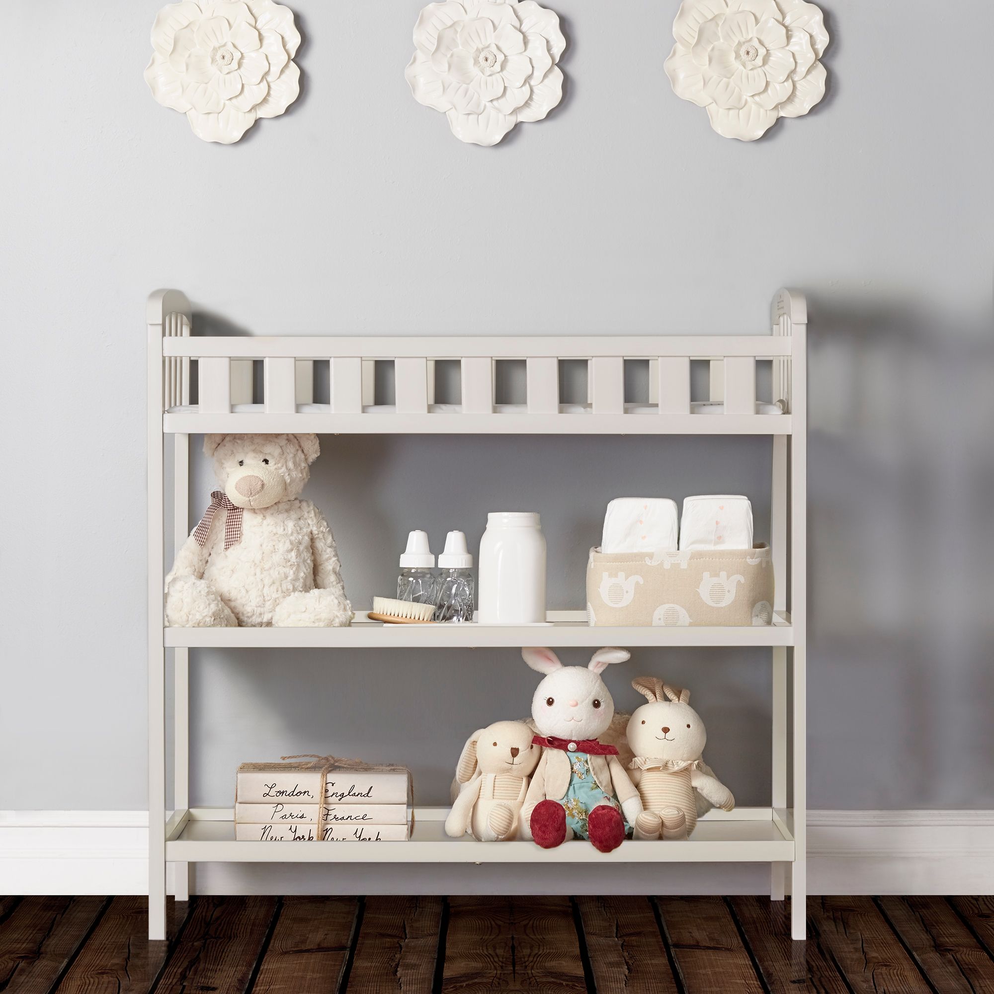 Dream On Me Emily Changing Table in White with open shelves, stocked with diapers, bottles, toys, and nursery essentials for organized storage