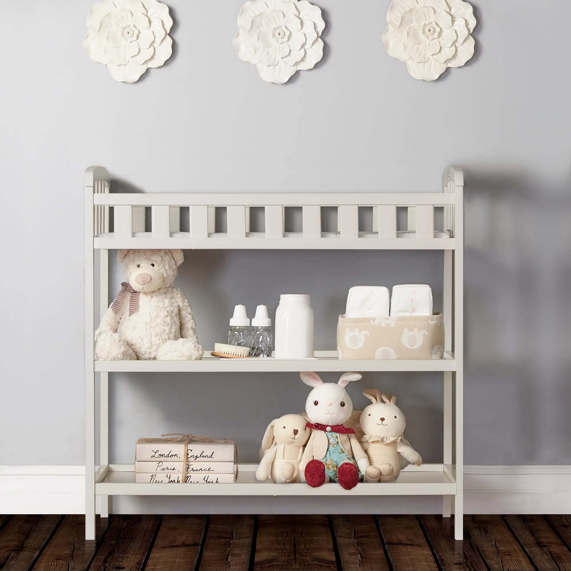 Dream On Me Emily Changing Table in White with open shelves, stocked with diapers, bottles, toys, and nursery essentials for organized storage