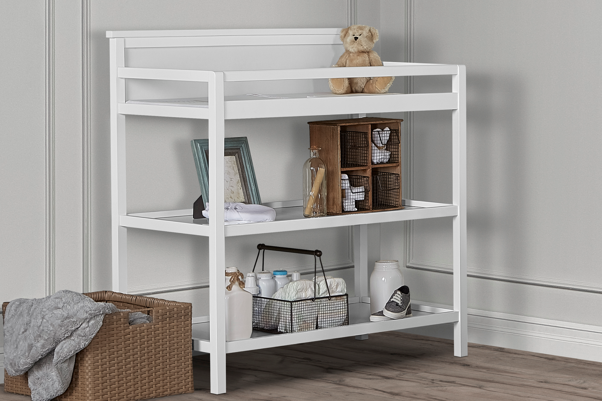 Dream On Me Jax Universal Changing Table with open shelving, styled with baby essentials, storage baskets, and decorative items set against a soft gray paneled wall.