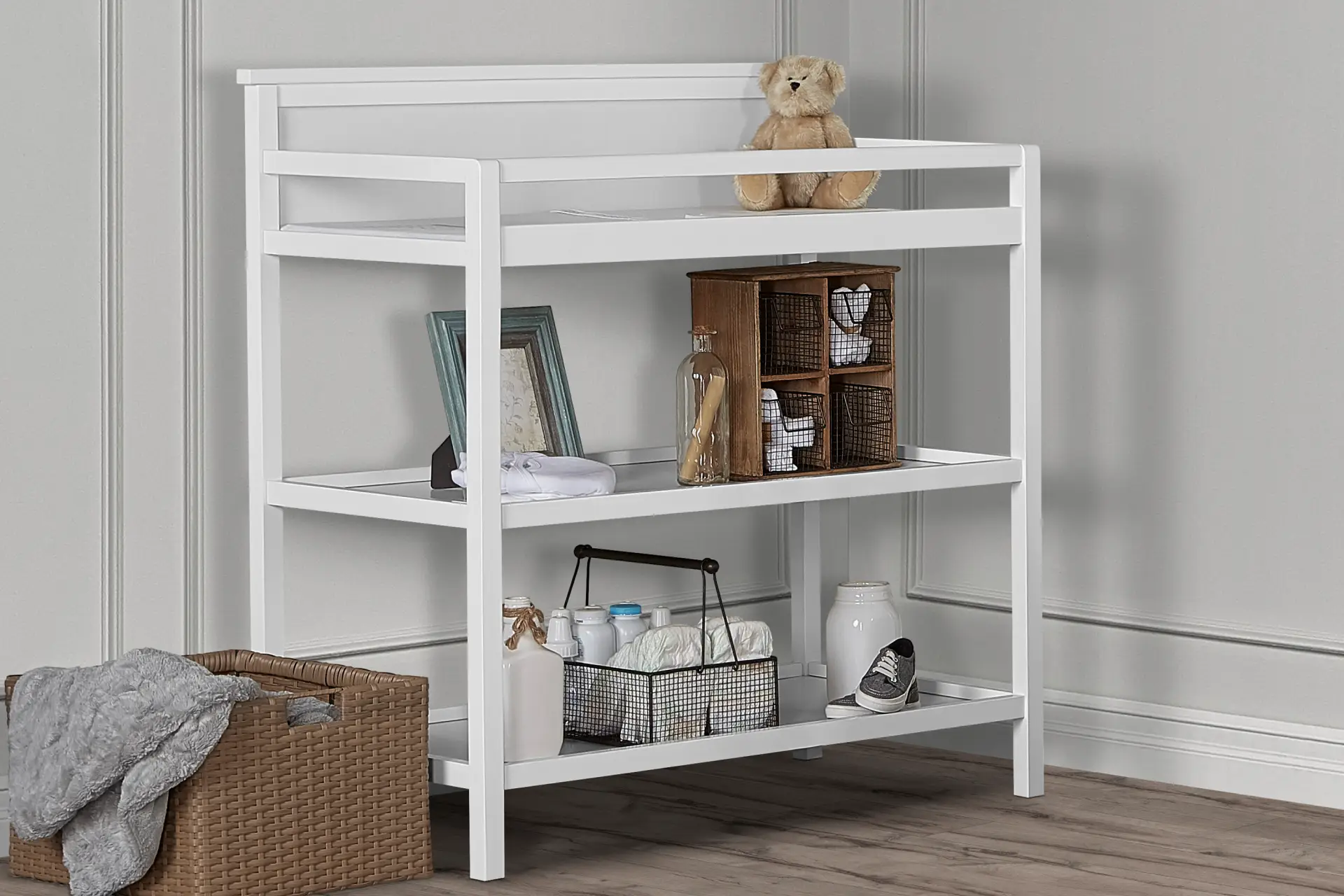 Dream On Me Jax Universal Changing Table with open shelving, styled with baby essentials, storage baskets, and decorative items set against a soft gray paneled wall.