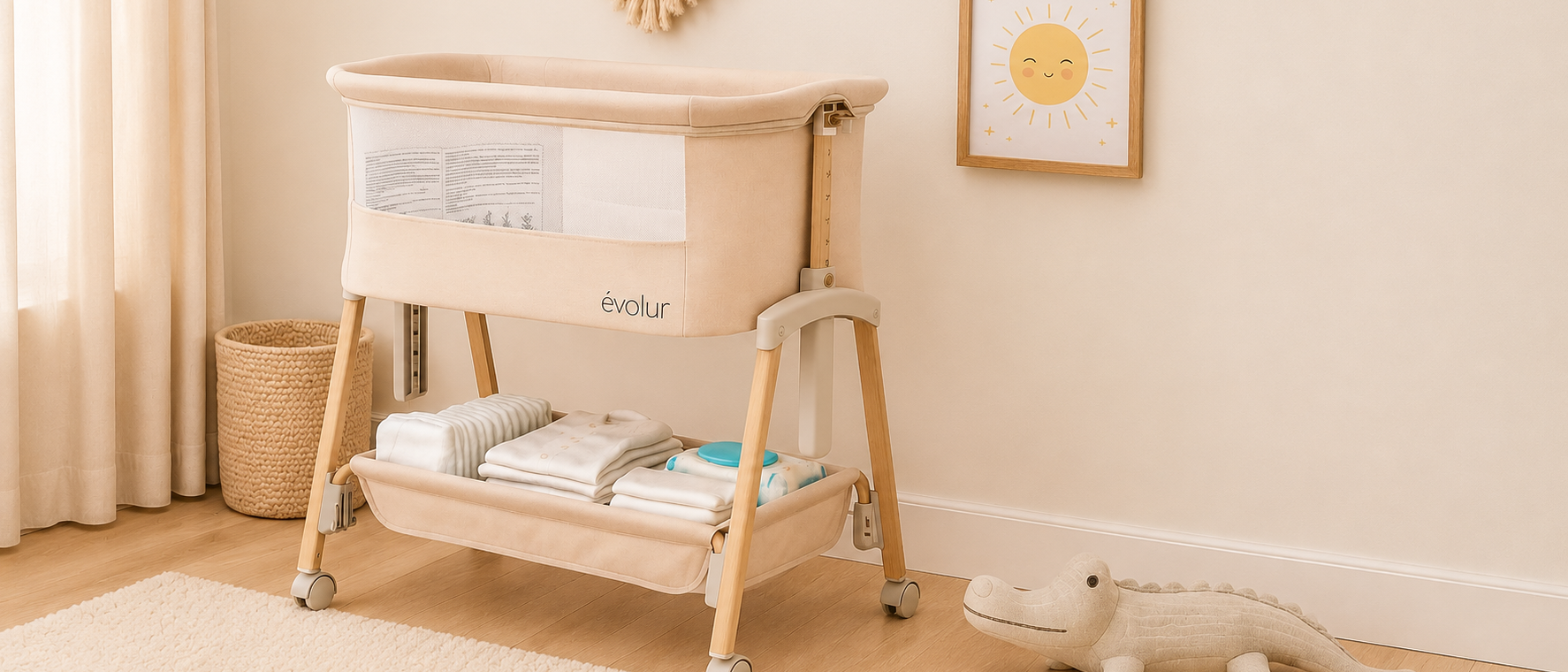 A beige Évolur baby bassinet with storage below, in a softly lit nursery with an alligator toy and sun picture.