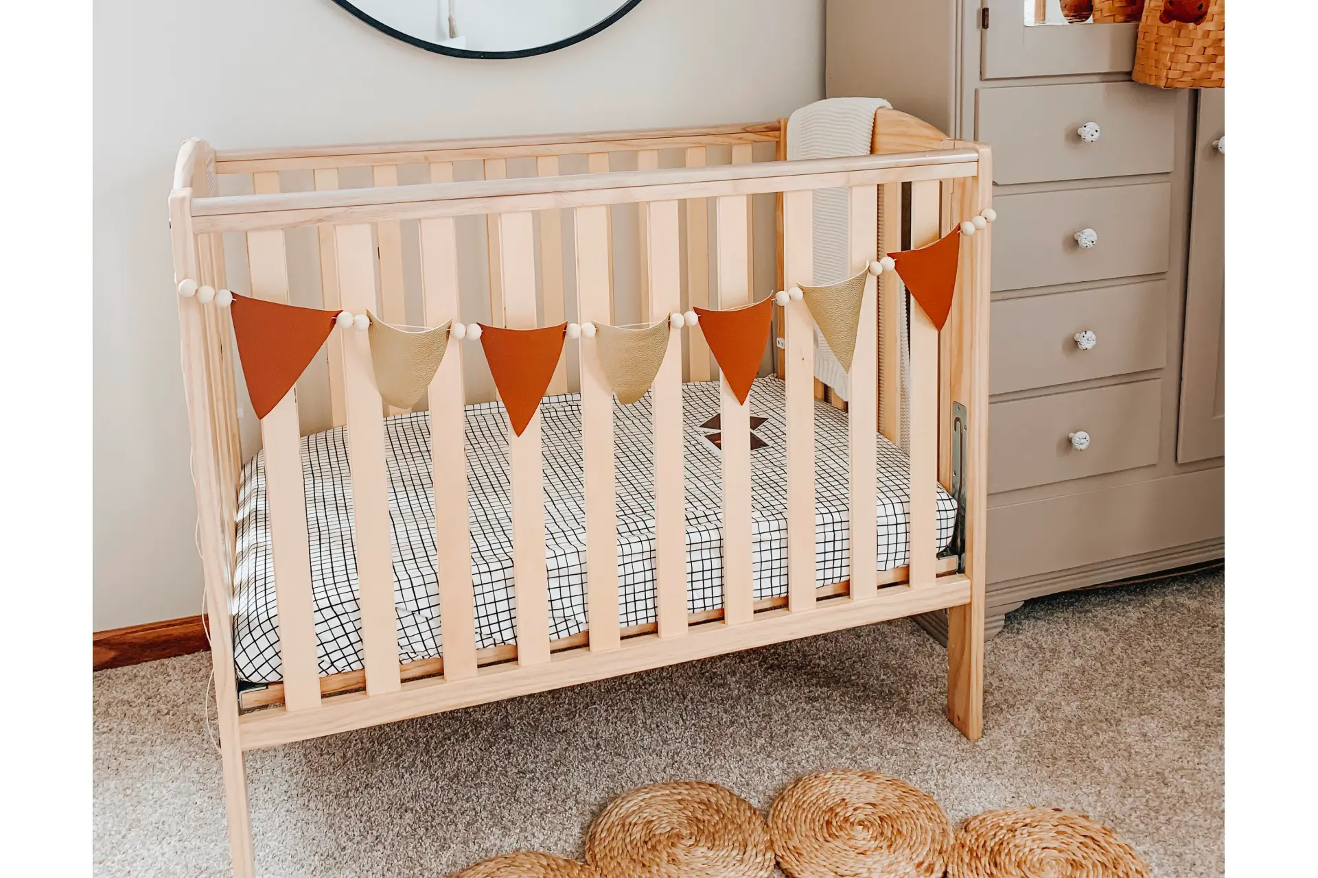 Boho-style nursery with Dream On Me Folding Full Size Crib, decorative bunting, woven accents, and neutral-toned storage cabinet.