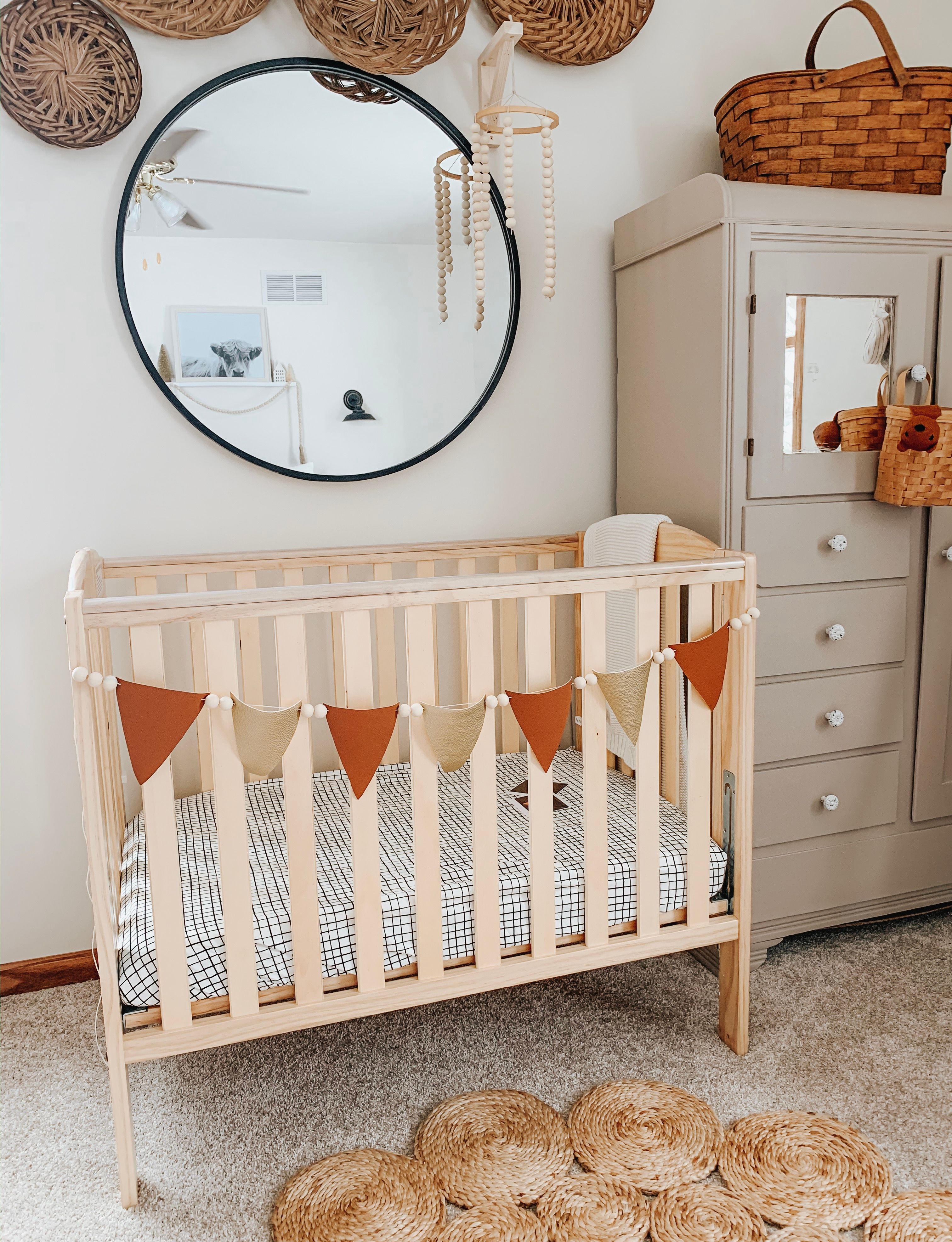 Boho-style nursery with Dream On Me Folding Full Size Crib, decorative bunting, woven accents, and neutral-toned storage cabinet