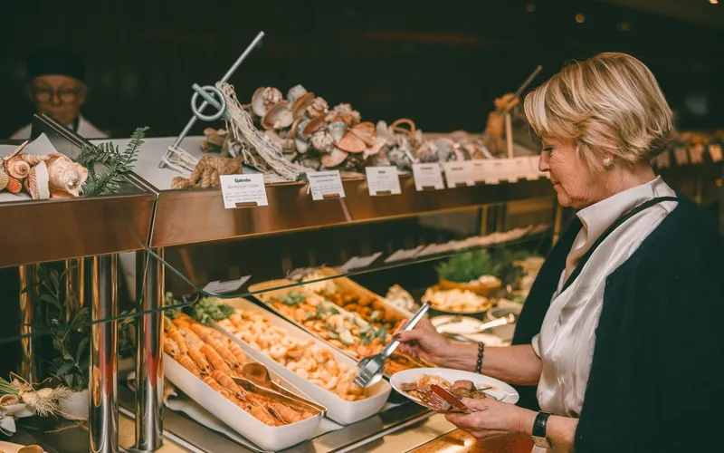 a woman is taking a plate of food from a buffet line .