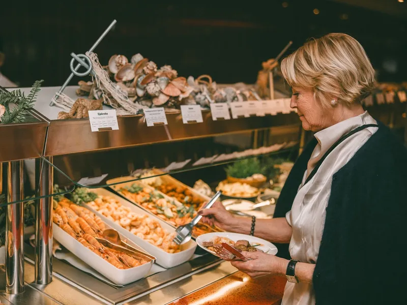 a woman is taking a plate of food from a buffet line .