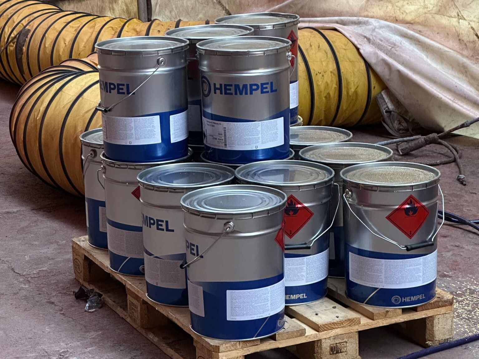 a bunch of buckets of paint are stacked on top of each other on a wooden pallet .