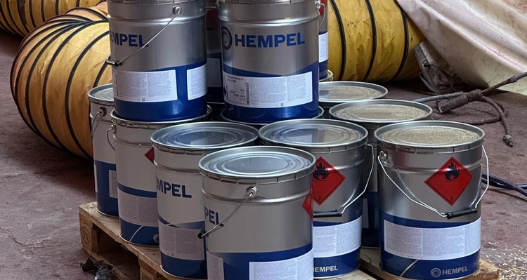 a bunch of buckets of paint are stacked on top of each other on a wooden pallet .