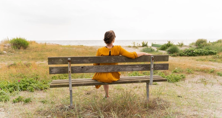 Dame sitter på en trebenk.