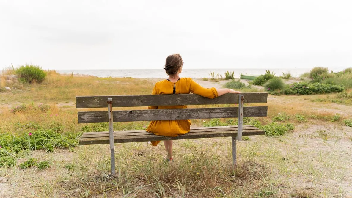 Dame sitter på en trebenk.