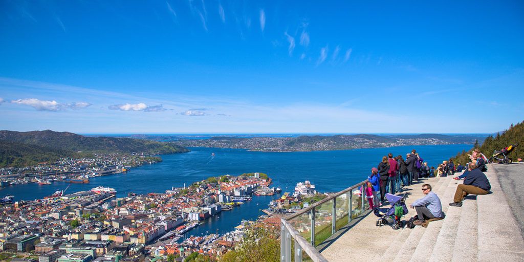 a group of people are sitting on a balcony overlooking a city and a body of water .