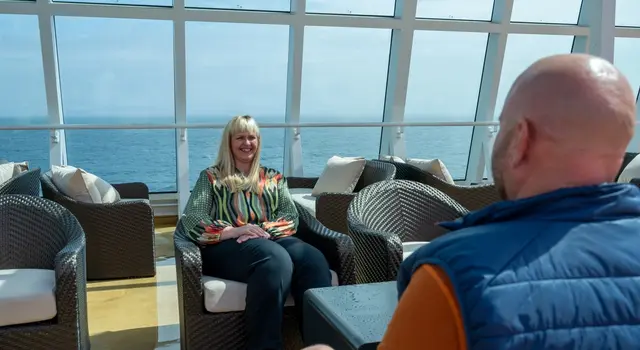 a man and a woman are sitting in chairs on a cruise ship .