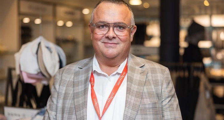 En mand med briller og nøglesnor står i en butik.