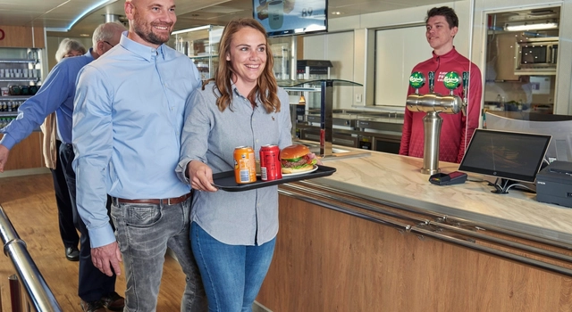 a man and a woman are standing next to each other in a restaurant holding a tray of food .