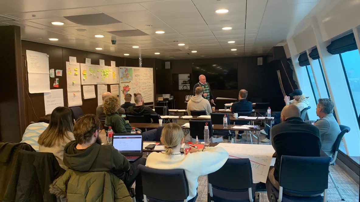 a group of people are sitting at tables in a conference room .