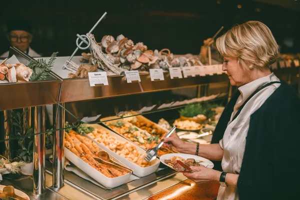 Dame forsyner seg i buffet.