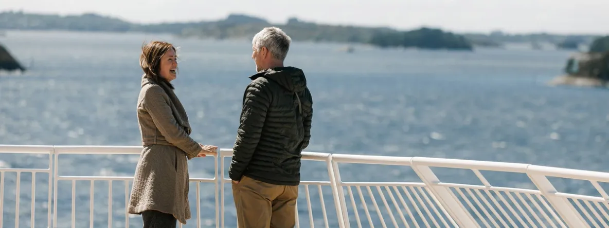 a man and a woman are standing on a balcony overlooking the ocean