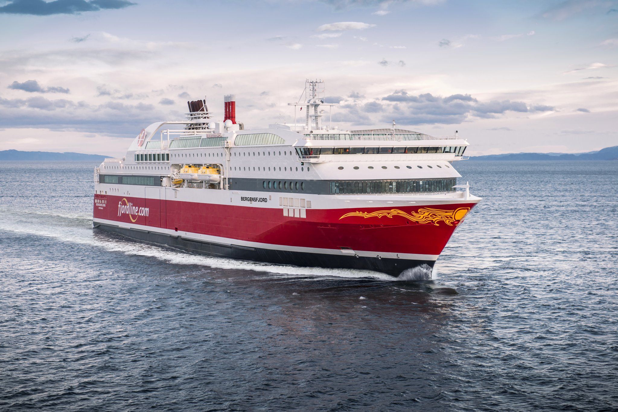 a large red and white cruise ship is floating on top of a body of water .