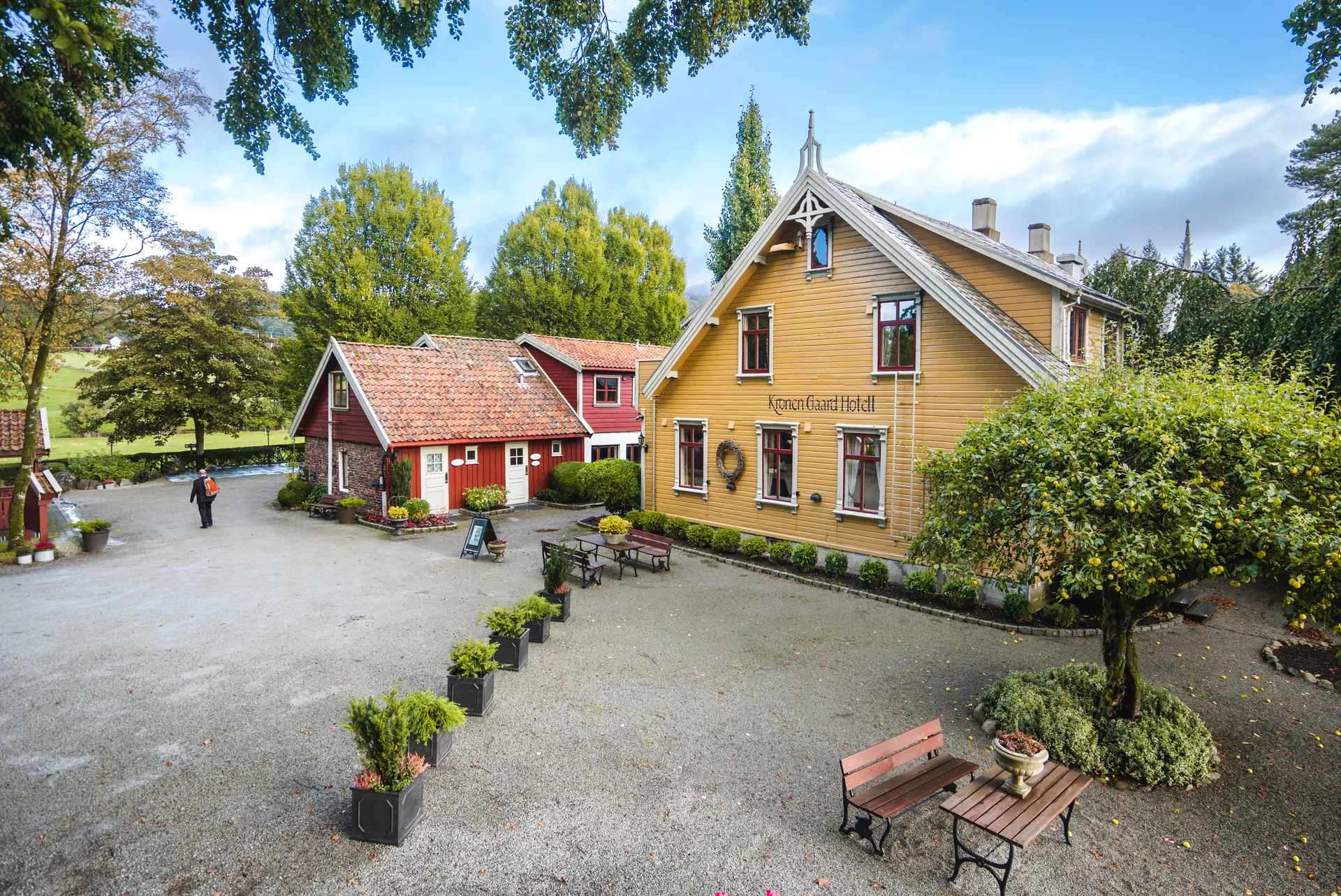 a yellow house with a red roof is surrounded by trees and bushes .