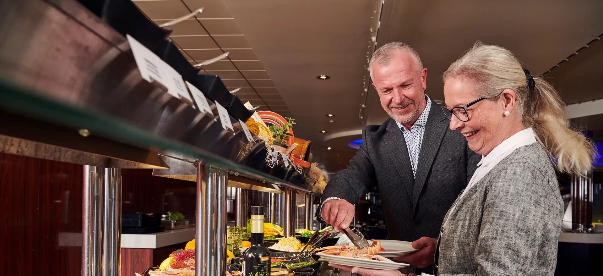 Dame og mann forsyner seg med mat fra buffet.