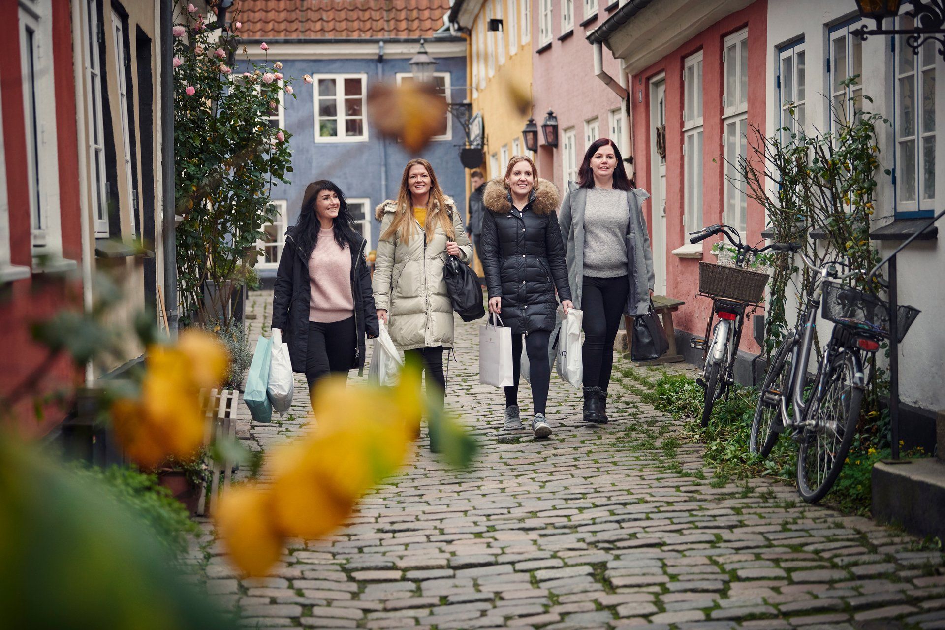 4 venninner spaserer i en koselig gate.