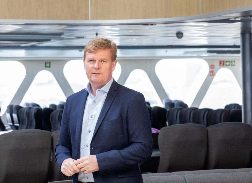 a man in a suit is standing in a room with empty seats .