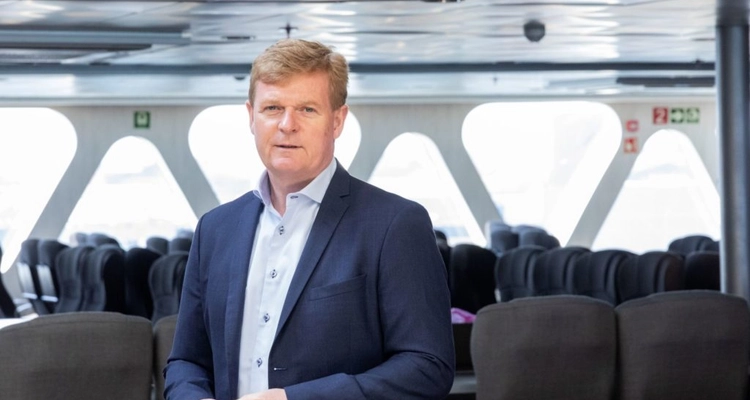 a man in a suit is standing in a room with empty seats .