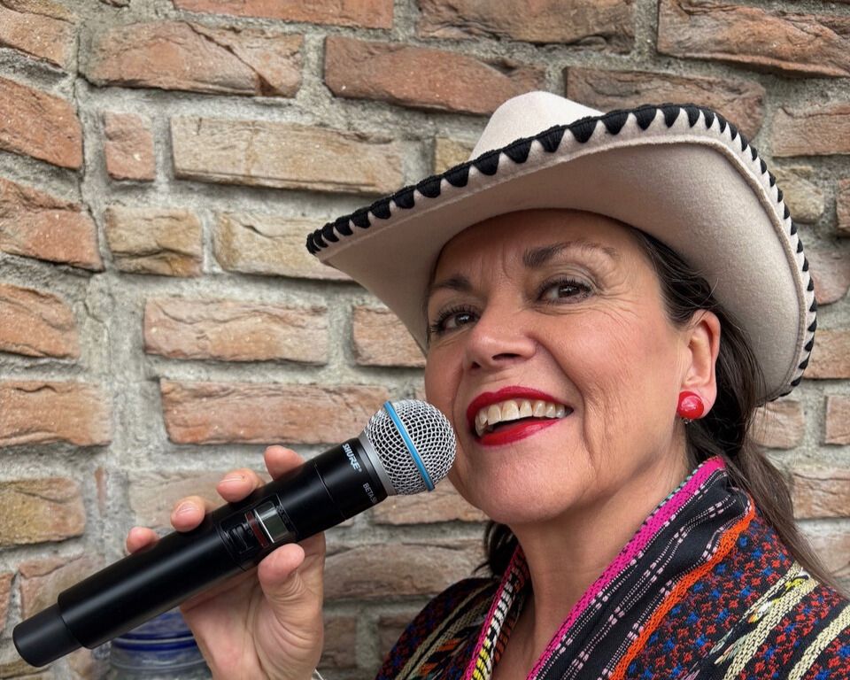 Dame med mikrofon og cowboyhatt.
