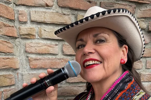 Dame med mikrofon og cowboyhatt.