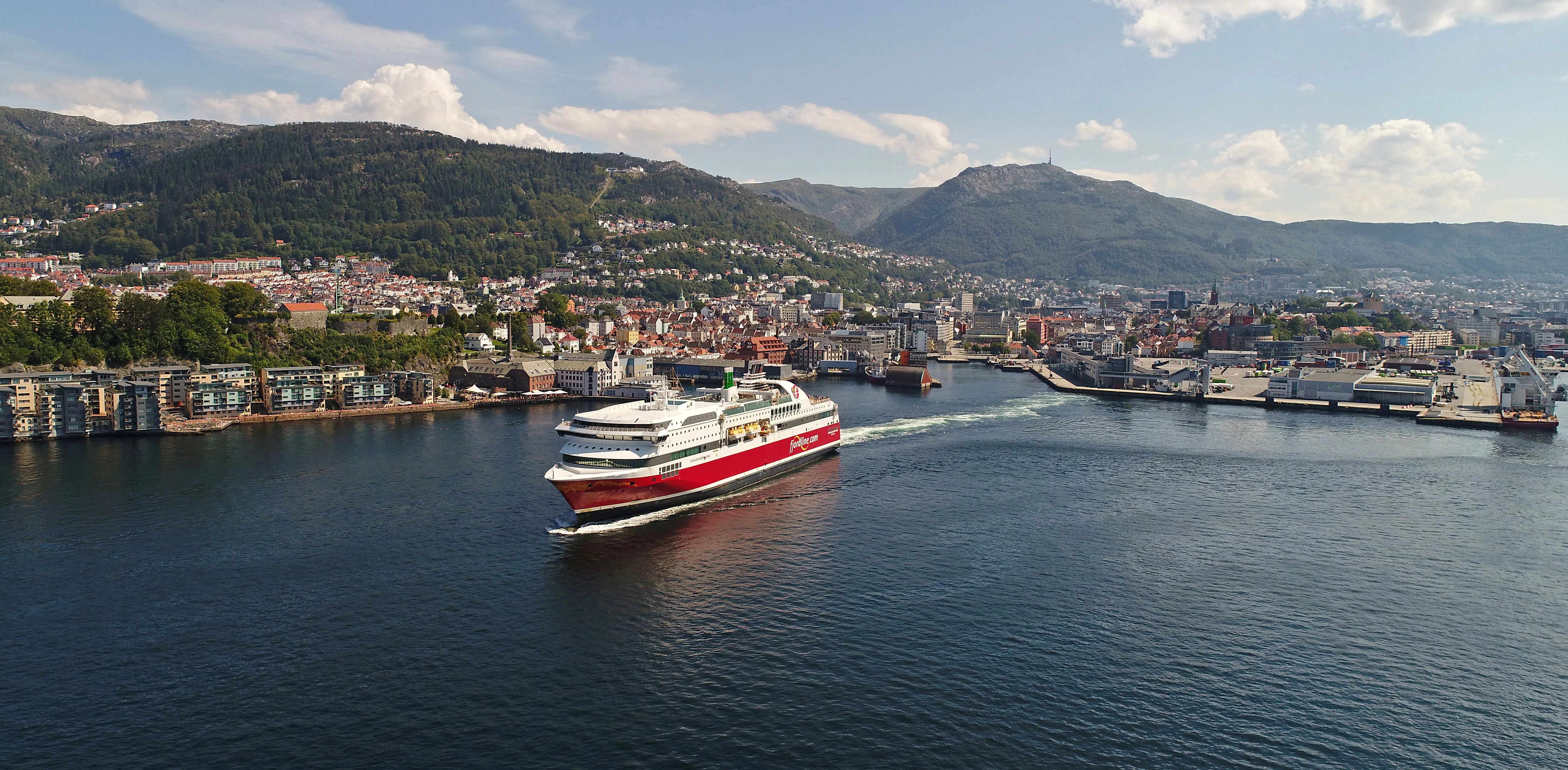 Rødt og hvitt skip på vei ut fra havnen i Bergen.