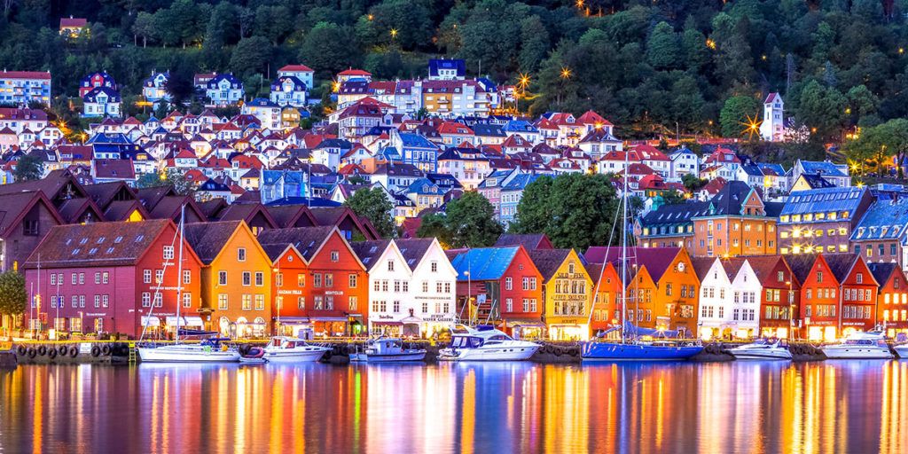a city with a lot of buildings and boats in the water at night .