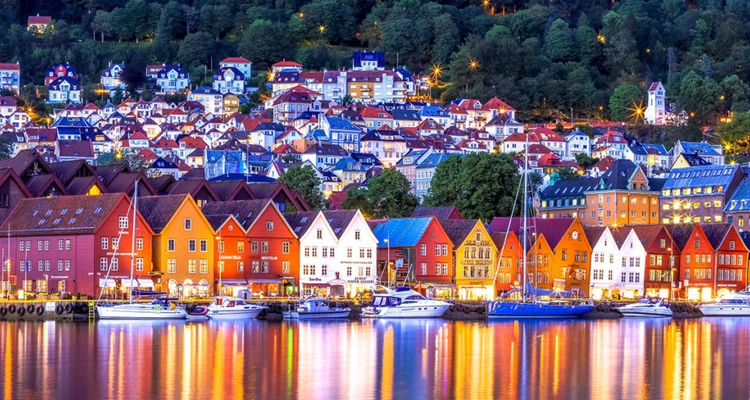 a city with a lot of buildings and boats in the water at night .