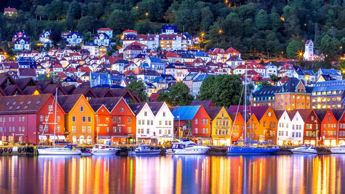 a city with a lot of buildings and boats in the water at night .