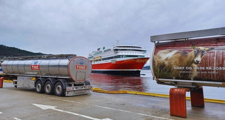 a large ship is docked next to a tanker truck .