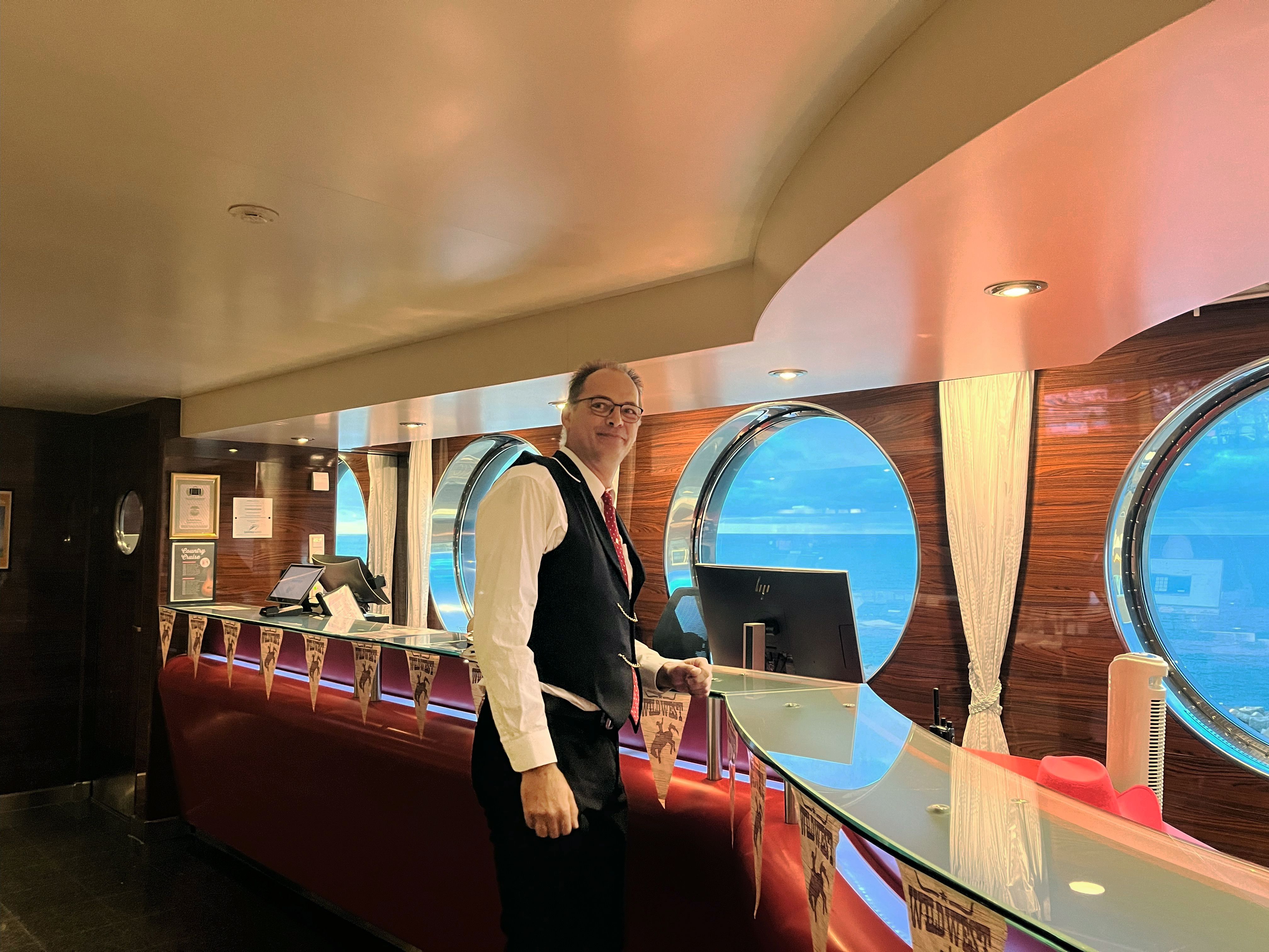 a man is standing at a counter in a restaurant .