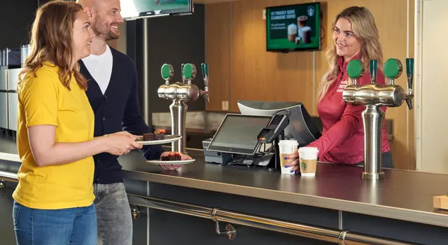 a man and a woman are standing at a counter in a restaurant .