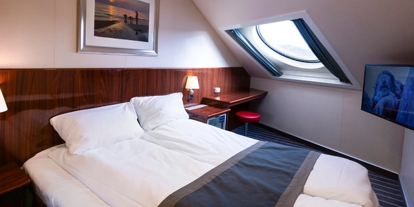 Lugar med dobbeltseng og rundt vindu med havutsikt.