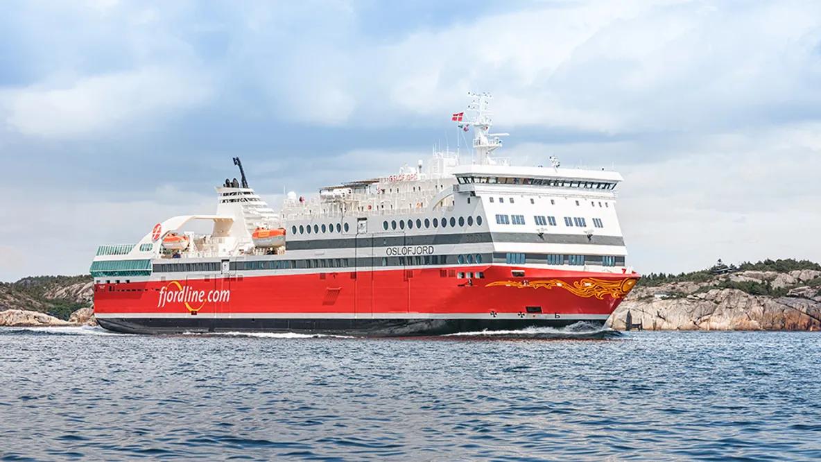 a large red and white cruise ship is floating on top of a body of water .